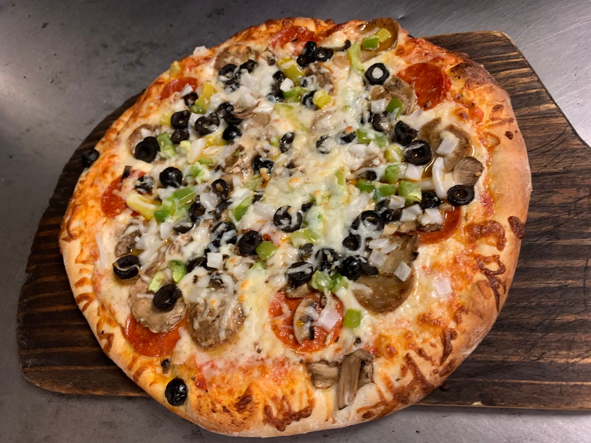 A fresh brick oven pizza on a wooden serving board